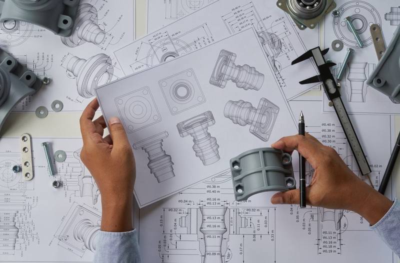 Engineer reviewing a technical drawing with a machined component